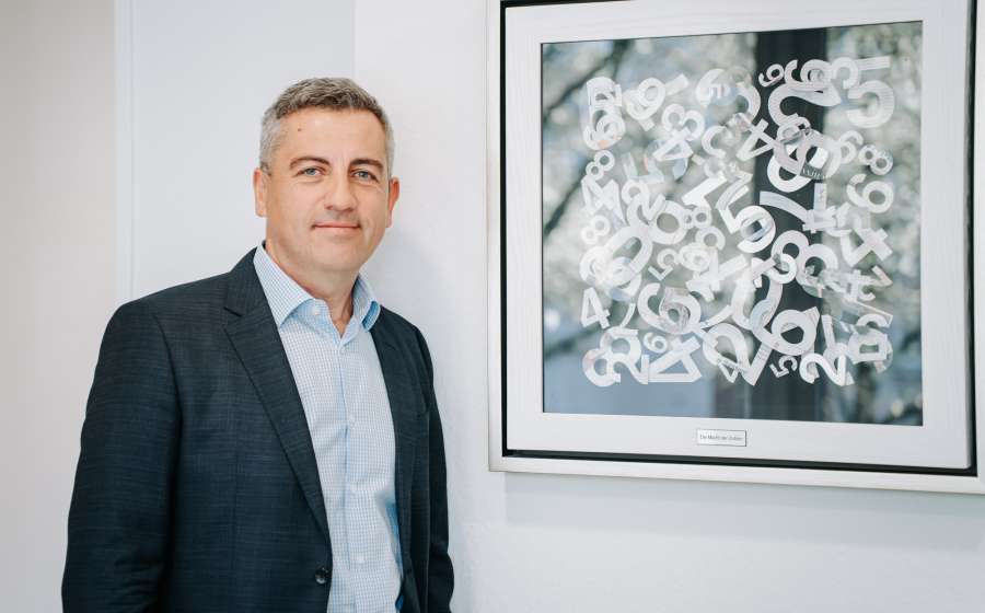 Steuerberater im Anzug vor einem abstrakten Kunstwerk im Büro