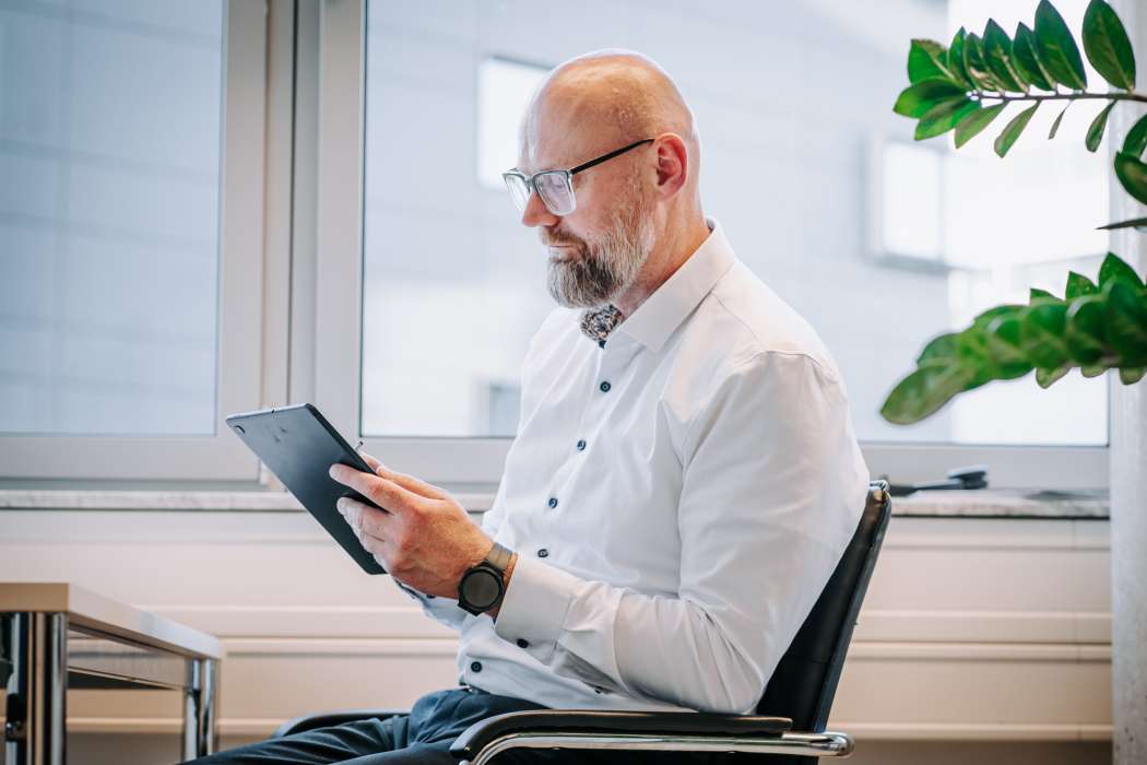 Steuerberater prüft Unterlagen auf Tablet im modernen Büro