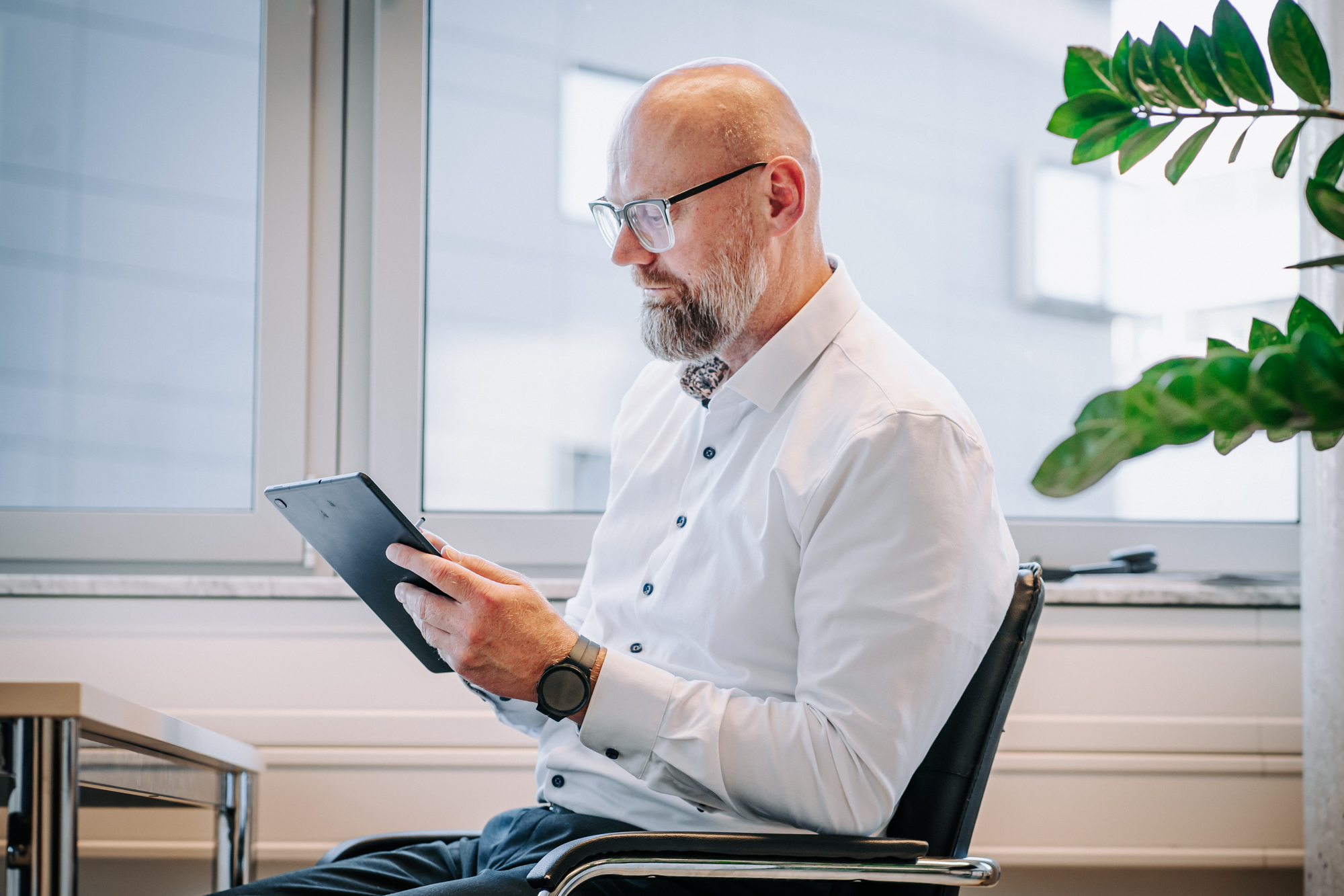 Steuerberater prüft Unterlagen auf Tablet im modernen Büro